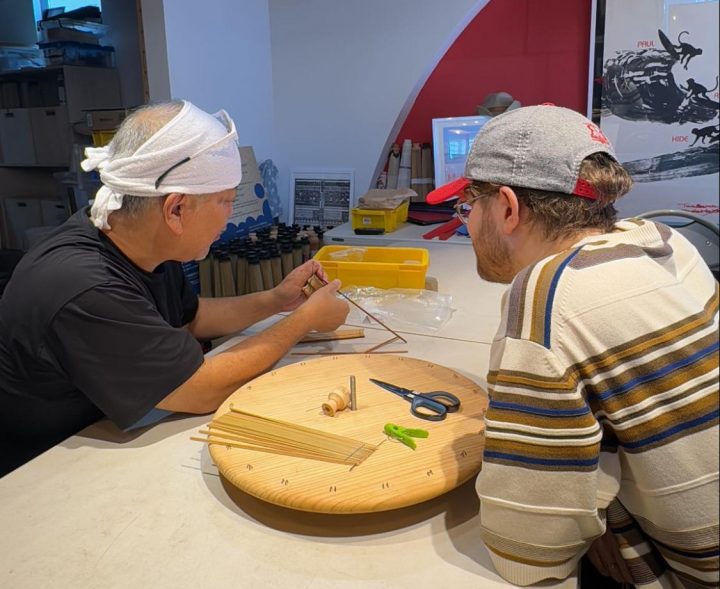 Hide teaching a workshop participant how to begin crafting a lampshade